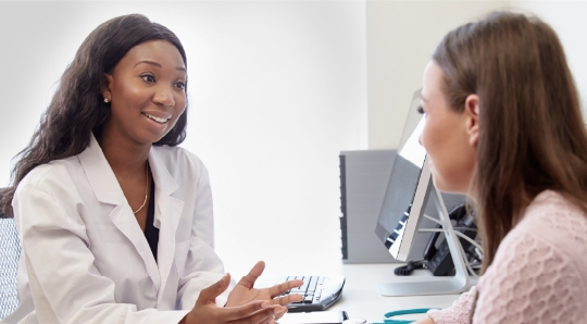 HCP and patient at desk discussing uterine fibroids